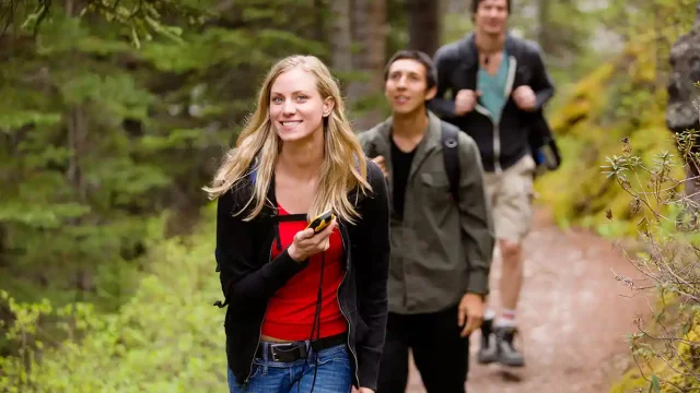 Femme avec un GPS en main sur un chemin de Chartreuse pendant une session de geocaching